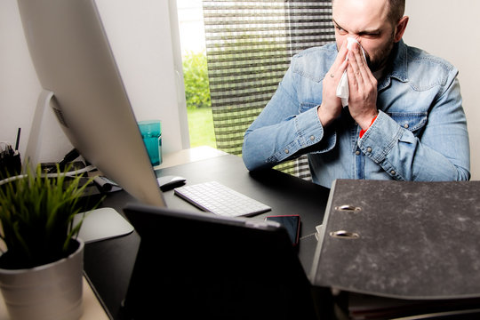 kranker Mann mit schnupfen am Arbeitsplatz