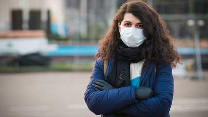 Close-up portrait young europeans woman in protective disposable medical face mask walking outdoors. Concept of health care