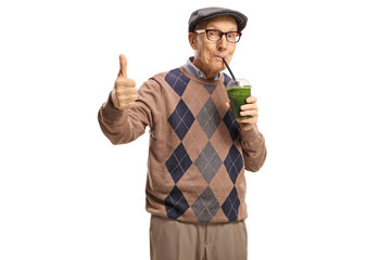 Senior man drinking a healthy green smoothie and showing thumbs up