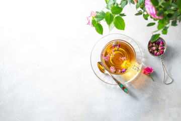 Pink tea buds, a glass cup and vintage strainer.