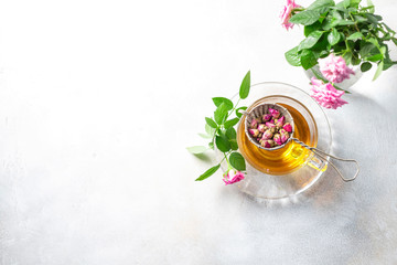 Pink tea buds, a glass cup and vintage strainer.