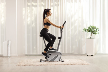 Young woman exercising on a stationary bike at home