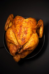 Whole roasted chicken in baking dish. Top view. Copy space. Macro shoot.