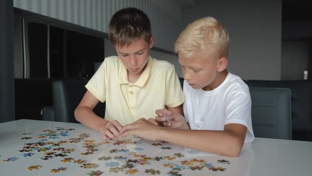 Two boys collect puzzles. Teamwork. Way to success. Happy family is engaged in self-development