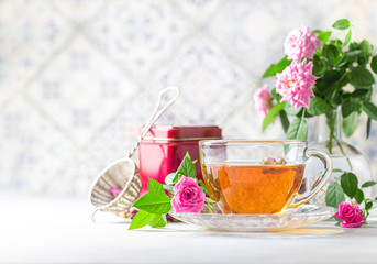 Pink tea buds, a glass cup and vintage strainer.