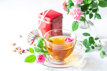 Pink tea buds, a glass cup and vintage strainer.