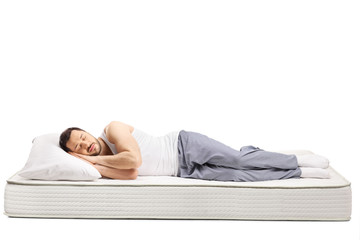 Young man sleeping on a comfortbale mattress isolated on white background