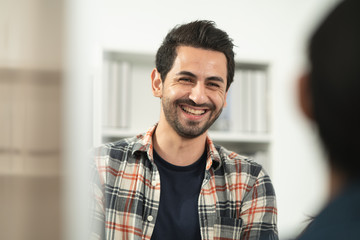 Fototapeta premium Portrait of Hispanic Arabian handsome beard man smiling and laughing enjoys the conversation with a selective focus, the concept of optimistic people, positive lifestyle.