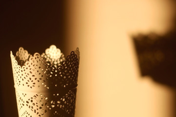 Intricate candle holder, illuminated by warm sunset light. Selective focus.