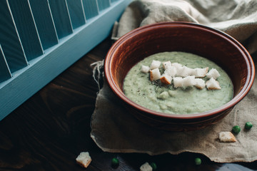 Green cream vegetable soup broccoli, peas, zucchini, spinach with croutons. Delicious vegetarian healthy food.