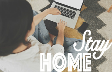 Stay home text and girl sitting on floor rug with laptop. Isolation at home to prevent virus...