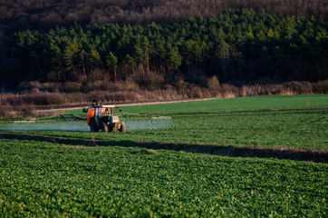 Tractor spraying poison on the plough field - pest control on the sowing - Europe