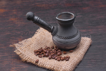 Black clay coffee turk and coffee grains on burlap.