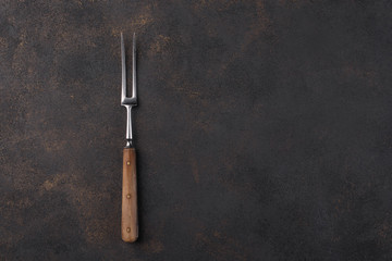Fork for meat on a dark background. Free space for an inscription.
