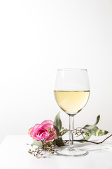 A glass of white wine with green flower twig on white background, isolated