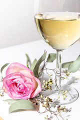 A glass of white wine with green flower twig on white background, isolated