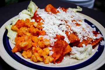 Enchiladas, platillo típico mexicano. Hecho con chiles guajillos y tortillas. Acompañado de cebolla, crema, queso, zanahorias, ppapas y lechuga