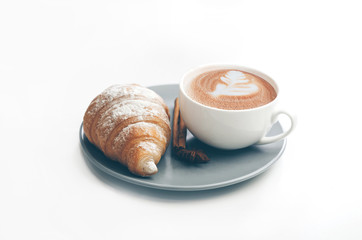 Fresh baked croissant with coffee cup and latte art, cinnamon
