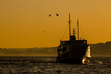 Fototapeta premium City passenger ship in silhouette going on the water when sunset time in the Istanbul of Turkey.