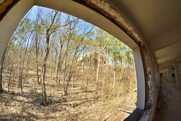 Widok z opuszczonego budynku przez okno na las i opuszczony budynek przez obiektyw fisheye.