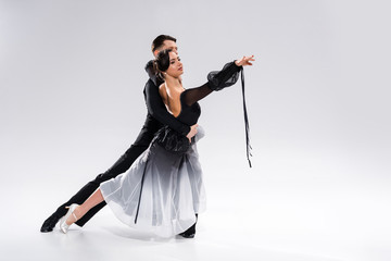 elegant young couple of ballroom dancers in black outfit dancing on white