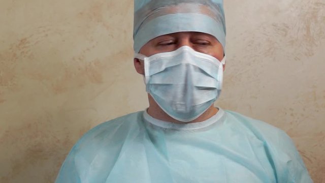 Doctor in a sterile gown, mask, cap and gloves talking
