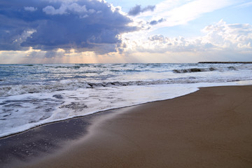 Fototapeta na wymiar Sunset on the seashore with reflection of cloudy sky on a wet sand on the beach
