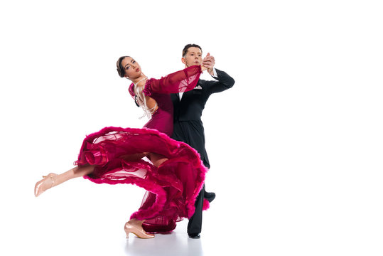 elegant young couple of ballroom dancers in red dress in suit dancing on white