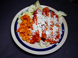 Enchiladas, platillo típico mexicano. Hecho con chiles guajillos y tortillas. Acompañado de cebolla, crema, queso, zanahorias, ppapas y lechuga