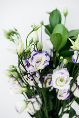 Beautiful bouquet of spring flowers in vase. Floral composition of fresh white violet eustoma flowers. Gift. Celebration concept. Blooming flowers.  