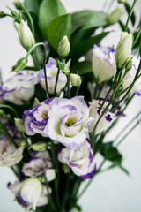 Beautiful bouquet of spring flowers in vase. Floral composition of fresh white violet eustoma flowers. Gift. Celebration concept. Blooming flowers.  