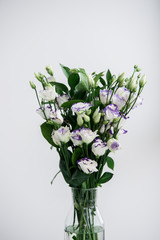 Beautiful bouquet of spring flowers in vase. Floral composition of fresh white violet eustoma flowers. Gift. Celebration concept. Blooming flowers.  