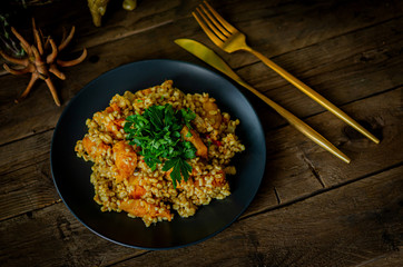 Bulgur with pumpkin on a wooden table. Vegetarian recipes from Indian cuisine.