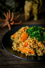 Bulgur with pumpkin on a wooden table. Vegetarian recipes from Indian cuisine.