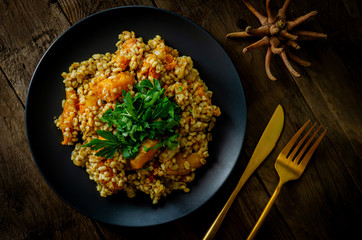 Bulgur with pumpkin on a wooden table. Vegetarian recipes from Indian cuisine.