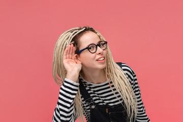 Young woman bending forward holding hand close to ear to hear important information.