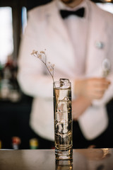 Gin and tonic cocktail in a highball glass decorated with a bunch of dried flowers. Light background. Smooth image with shallow depth of field.