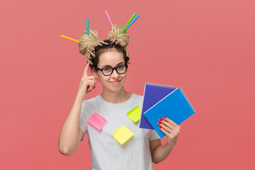 Student with sticky notes on a shirt and markers in dreads holding notebook and pointing at head