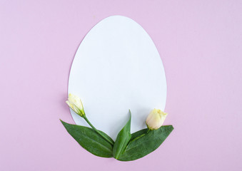 Easter creative composition.  Flat lay with shape of easter egg, frame  of flowers on pink  background. Minimal spring concept. Copy space