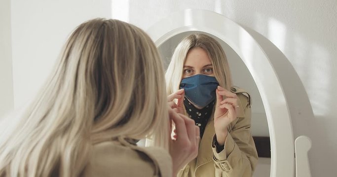 Young woman puts on a mask for protection against flu, long distance communication. Staying connected, Social distancing. Go out from her house on street.