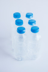 Close-up shot of plastic bottles of water in transparent wrap on white surface