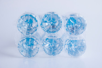 Close-up shot of plastic bottles of water in transparent wrap on white surface