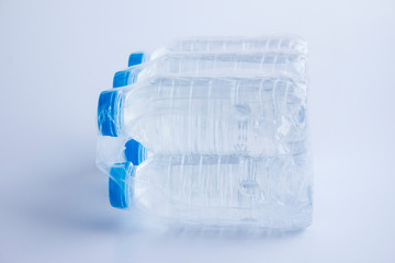 Close-up shot of plastic bottles of water in transparent wrap on white surface