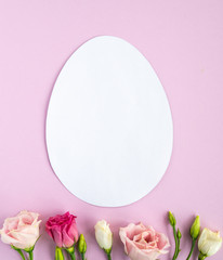 Easter creative composition.  Flat lay with shape of easter egg, frame  of flowers on pink  background. Minimal spring concept. Copy space
