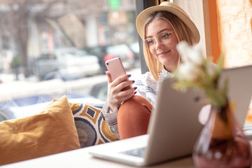 Young woman sitting in cafe shop and using smartphone.