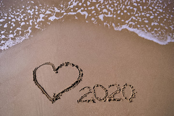 Heart and year 2020 written on sand on the beach