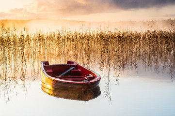 Obrazy na Szkle  Czerwona łódź na wciąż mglistym jeziorze o wschodzie słońca