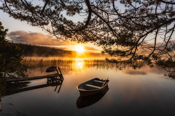 Row boat on still lake at sunrise