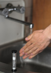 man washing his hands in kitchen sink, sand clock, hygiene