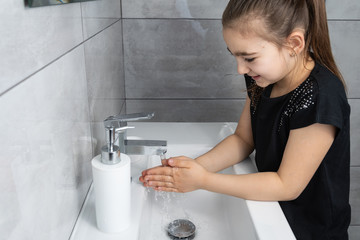 Dziewczynka myje ręce w łazience. Mycie i dezynfekcja rąk mydłem i płynem antybakteryjnym.